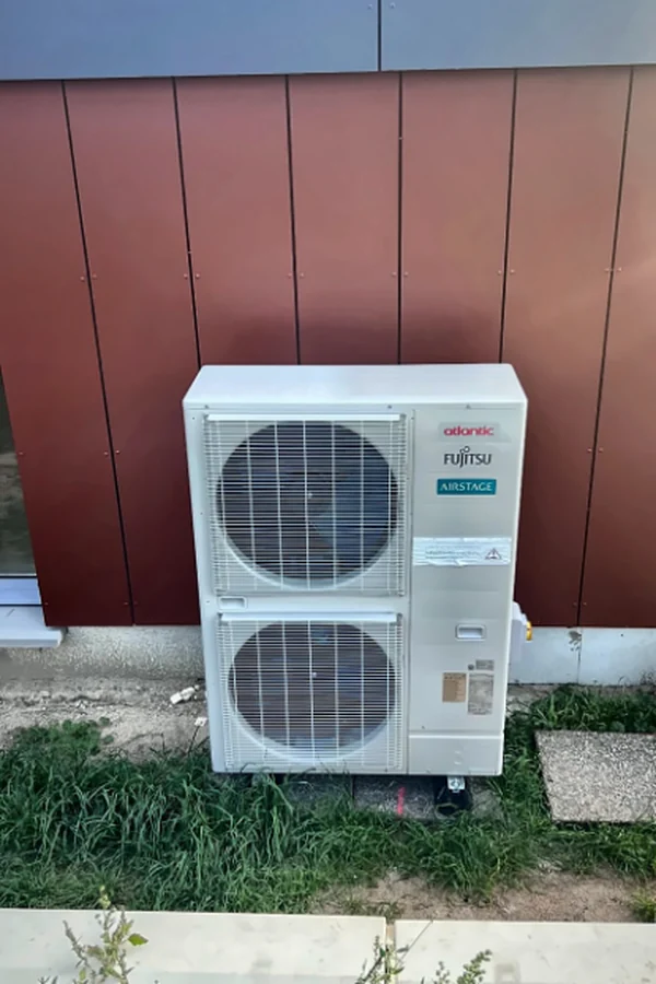 Groupe extérieur de climatisation Atlantic Fujitsu Airstage installé contre la façade d'une école maternelle à Saint-Laurent-Nouan (41).
