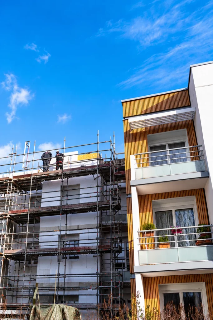 Travaux de rénovation énergétique d’un immeuble collectif avec pose d’isolation extérieure sur échafaudages.